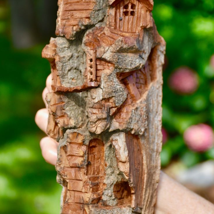 a person holding up a piece of wood carved to look like a castle or building