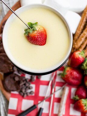 a strawberry on top of a drink in a glass next to strawberries and crackers