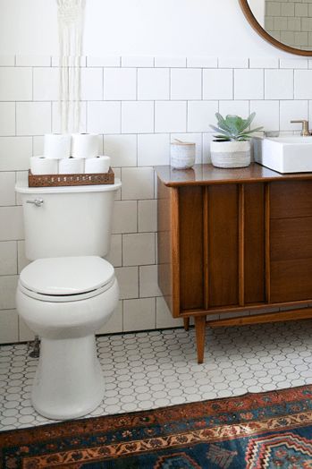 a white toilet sitting in a bathroom next to a wooden cabinet and mirror on the wall