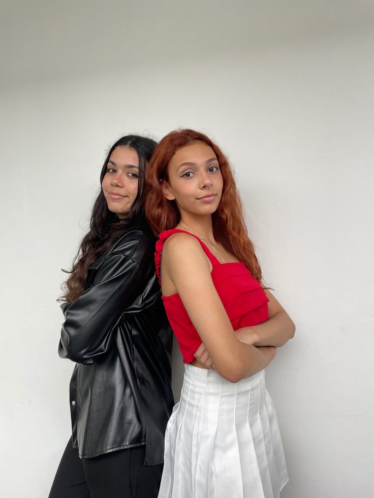 two women standing next to each other in front of a white wall