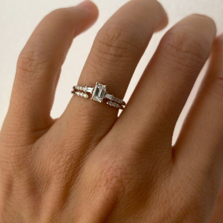 a woman's hand with a diamond ring on top of her finger and two diamonds in the middle