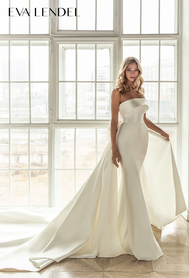 a woman in a white wedding dress posing for the camera with her hand on her hip