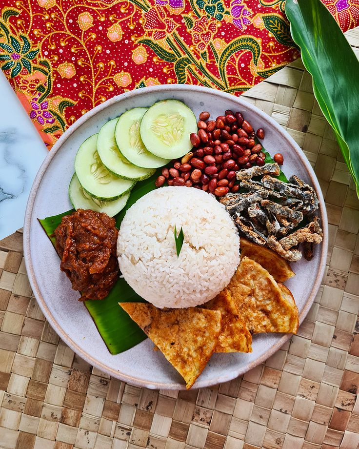 a plate with rice, beans, cucumbers and other food items on it