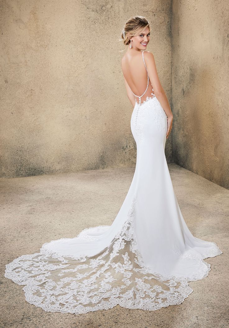 a woman in a white wedding dress posing for the camera with her back to the camera