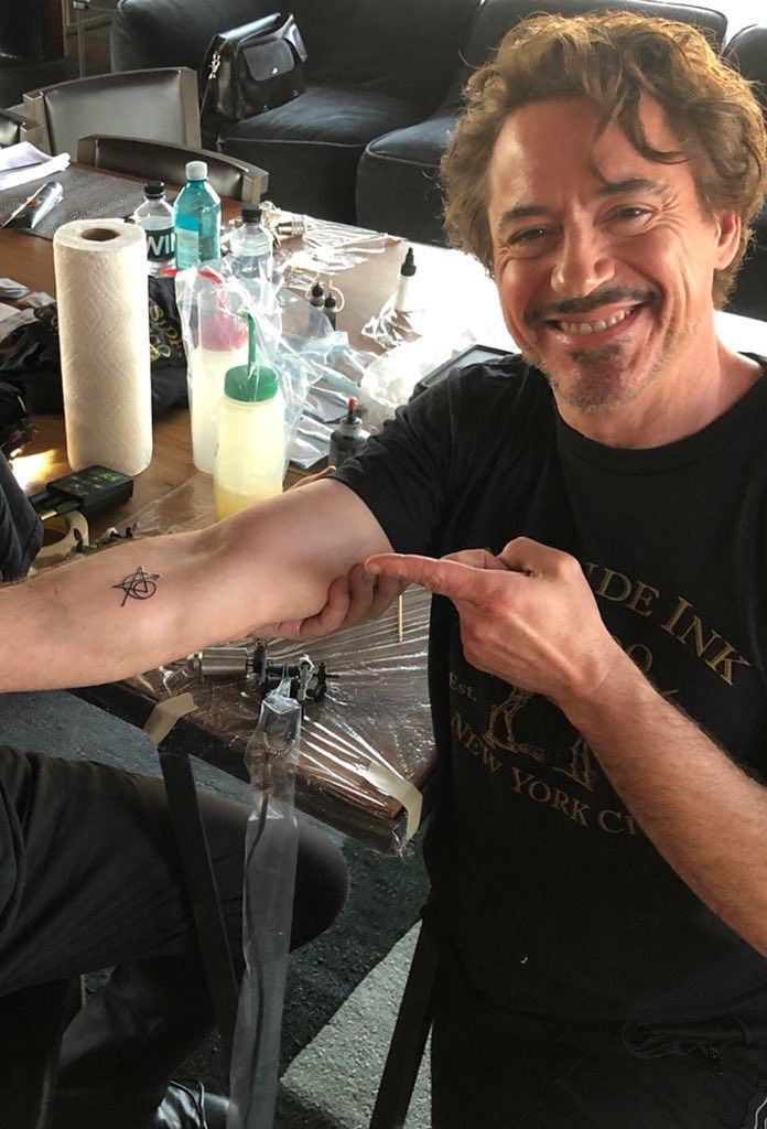 a man with a tattoo on his arm is sitting at a table in front of some bottles