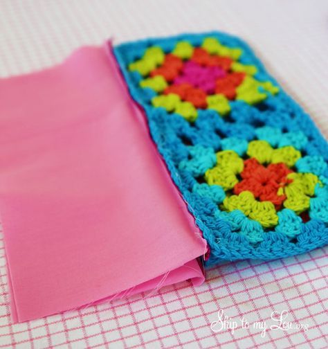 a crocheted piece of cloth sitting on top of a table next to a pink napkin