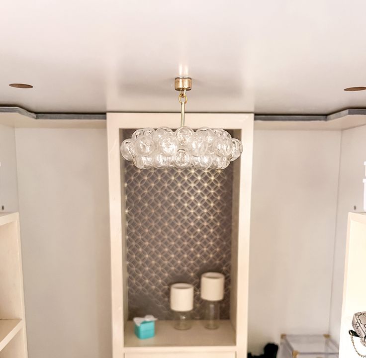 a room with a shelf, shelves and a chandelier hanging from the ceiling