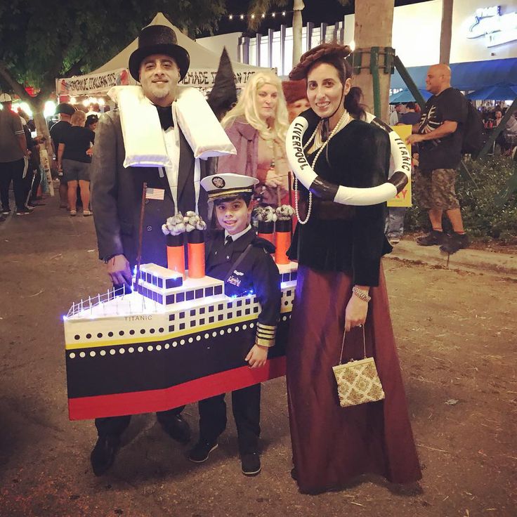 three people dressed up in costumes standing next to a cake shaped like a boat with a man on it