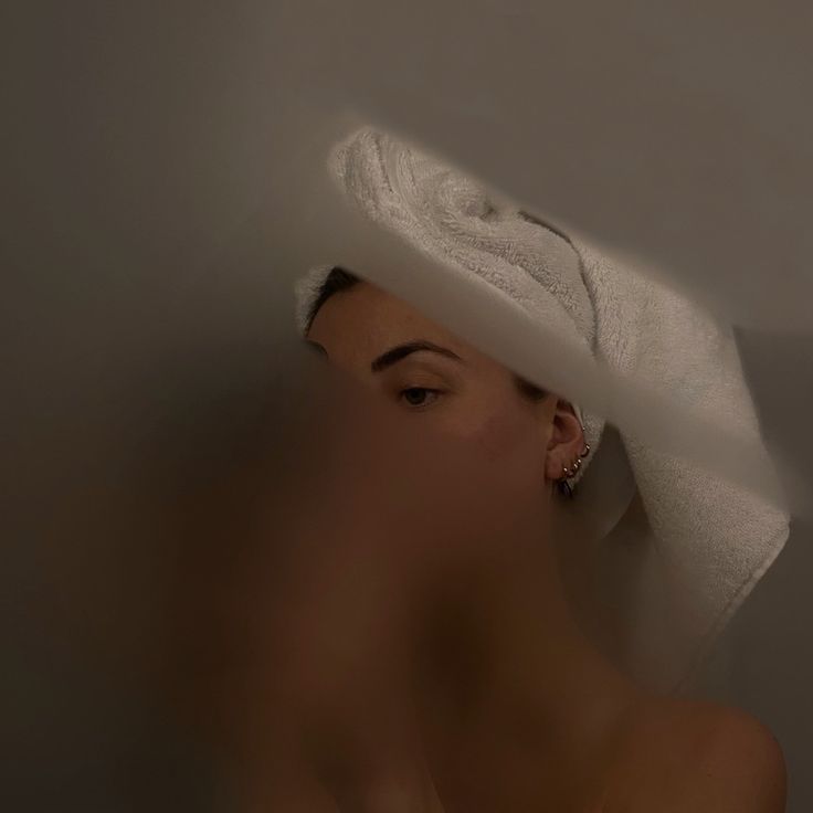 a woman with a towel on her head in a bath room next to a wall