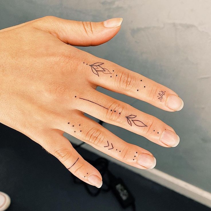 a woman's hand with tattoos on it and an arrow tattooed on the middle finger