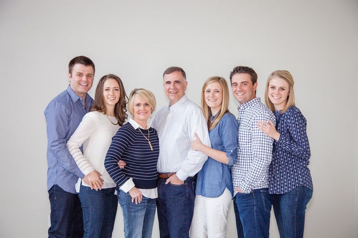 a group of people standing next to each other in front of a white wall with their arms around each other