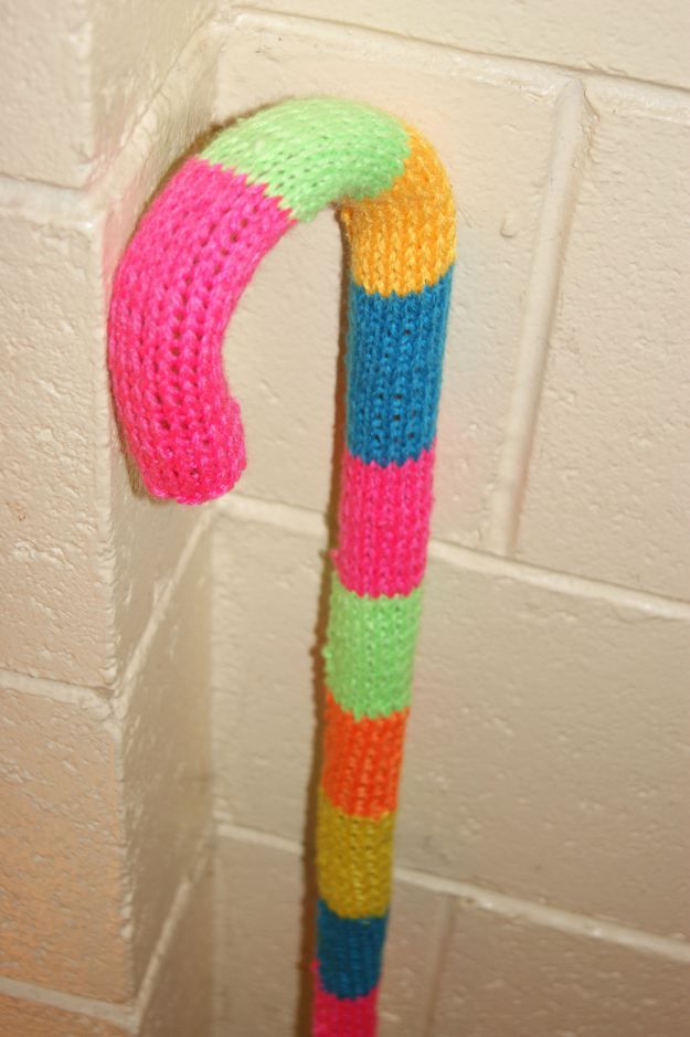 a knitted candy cane hanging from the side of a wall