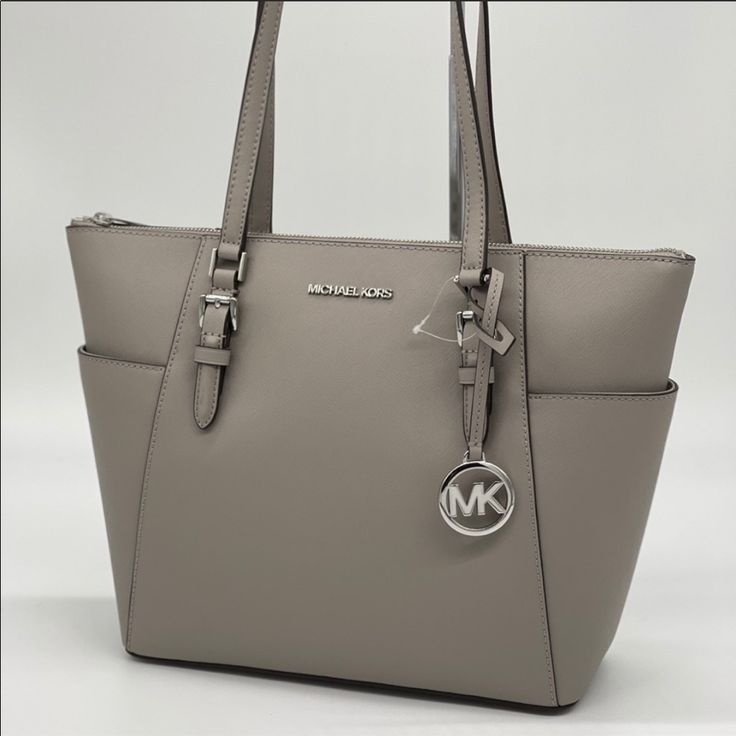 Brand New With Tag Michael Kors Charlotte Large Top Zip Tote Color: Pearl Grey Silver Toned Hardware 2 Slip-In Back Pocket On Side Pvc Leather With Pebbled Leather Trim 1 Mk Circle Charm Zip Top Closure Custom Fabric Lining Interiors: 2 Slip-In Pockets And 1 Zipped Pocket 15"(Top) 11"(Bottom) X 10"(H) X 4.5"(D) Straps: 9.5" Dust Bag Not Included Shoulder Bag With Silver-tone Logo Plaque For Everyday Use, Modern Travel Bag With Silver-tone Logo, Modern Travel Bags With Silver-tone Logo Plaque, Modern Travel Bag With Silver-tone Logo Plaque, Silver-tone Logo Plaque Shoulder Bag, Classic Shoulder Bag With Silver-tone Logo Plaque, Travel Bags With Silver-tone Logo Plaque, Chic Bags With Silver-tone Logo Plaque For Everyday Use, Elegant Gray Bag With Silver-tone Hardware