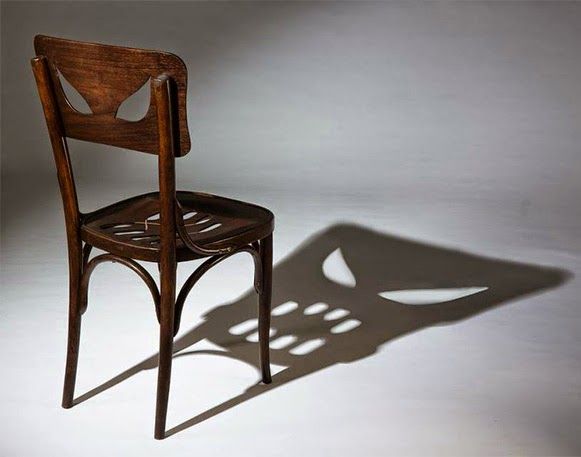 a black and white photo of a chair casting a shadow