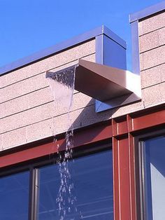 a water spouting out of the side of a building's window sill