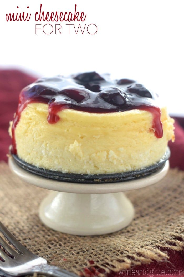 a cheesecake with blueberries on top is sitting on a white cake platter