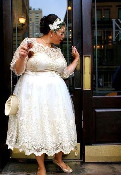 a woman standing in front of a door wearing a white dress and holding a purse