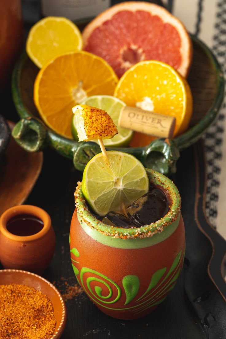 an orange and lime drink in a clay pot with garnish on the rim