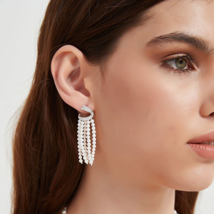 Transform your look with our Luxurious Curved Cubic Zirconia & Multi-Chain Pearl Earrings, a sophisticated blend of sparkle and elegance. The design features a gracefully curved band of brilliant cubic zirconia at the top, leading to five delicate chains adorned with lustrous 3-4mm freshwater pearls. Crafted meticulously in sterling silver, these earrings exude opulence and charm, making them a striking accessory for luxury events or whenever you desire to infuse a touch of glamour into your att White Diamond Crystal Earrings, Glamorous, White Diamond Crystal Glamorous Earrings, Glamorous White Diamond Crystal Earrings, White Diamond Chandelier Earrings For Party, Elegant Diamond White Cubic Zirconia Chandelier Earrings, Elegant Diamond White Crystal Chandelier Earrings, Glamorous White Diamond Earrings With Sparkling Stones, Elegant Crystal Chandelier Earrings In Diamond White, Elegant Sparkling Drop Chandelier Earrings