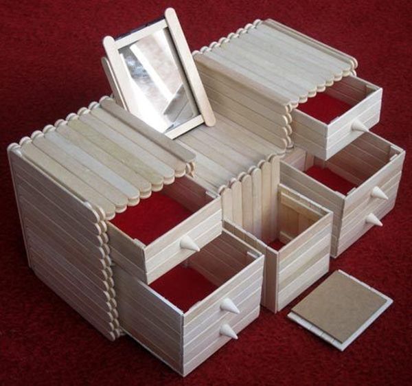 a small wooden box with drawers and a mirror on the top, sitting on a red carpeted floor