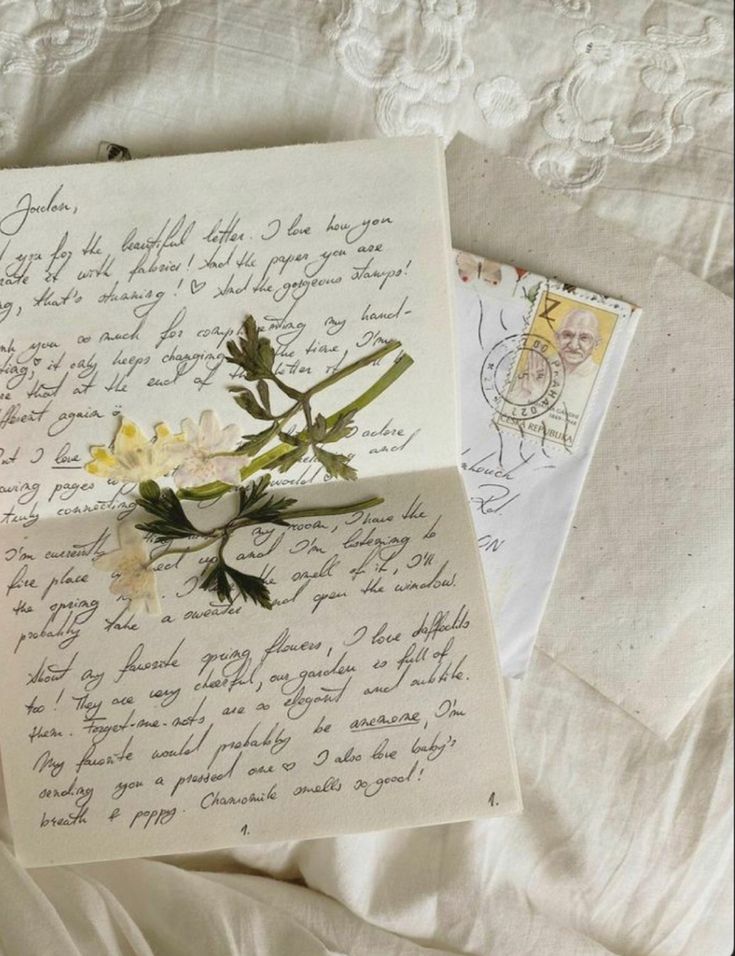 an old letter with flowers on it laying on a bed