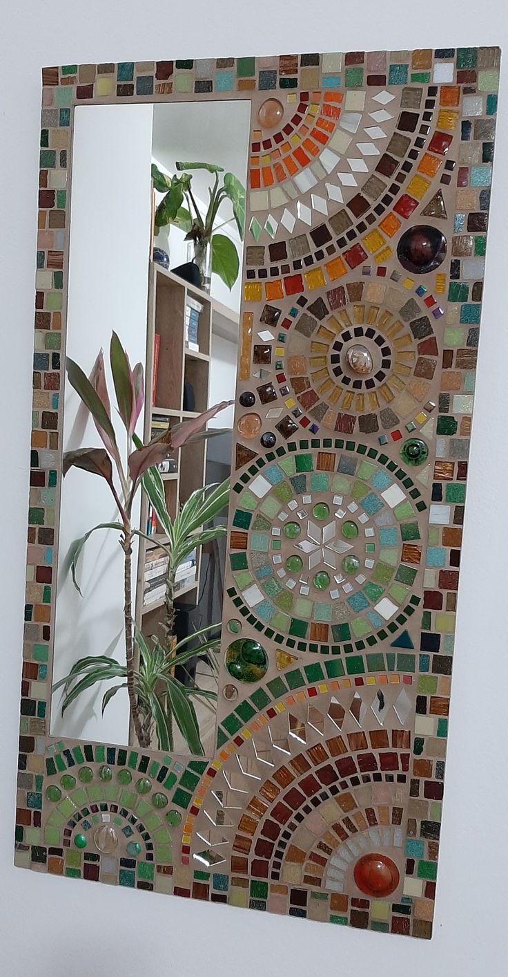 there is a mirror that has been made out of mosaic tiles and plants in it