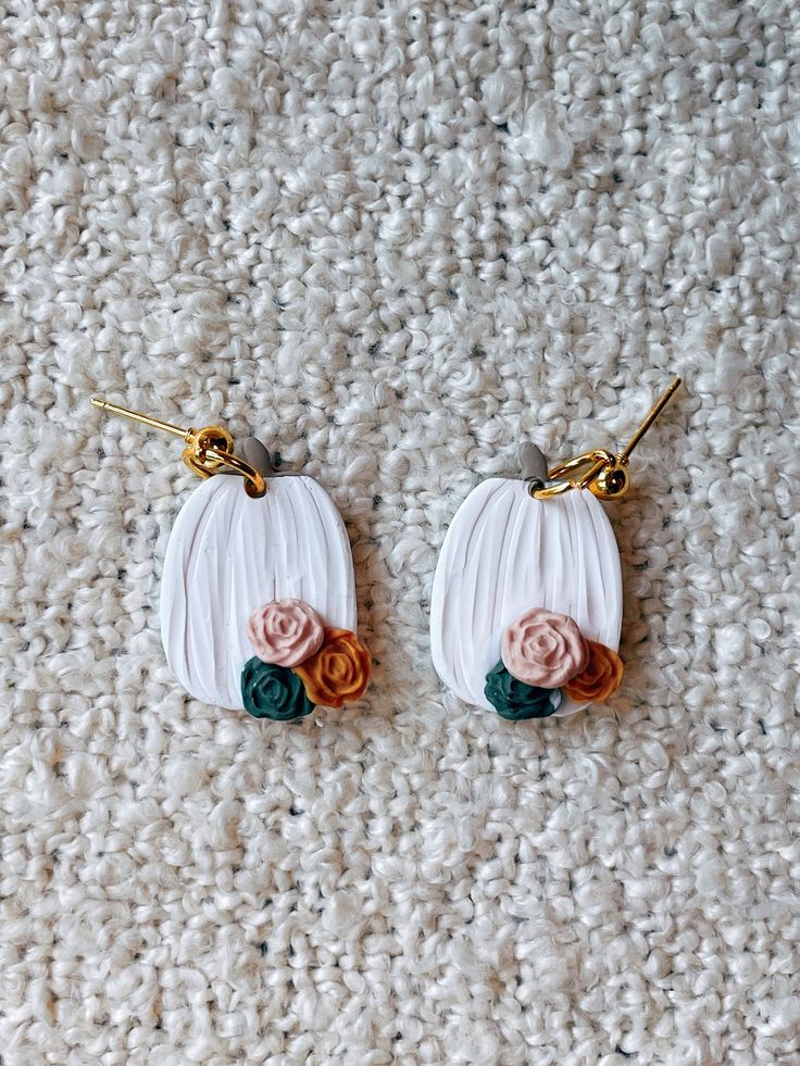 two earrings with flowers on them sitting on a carpet