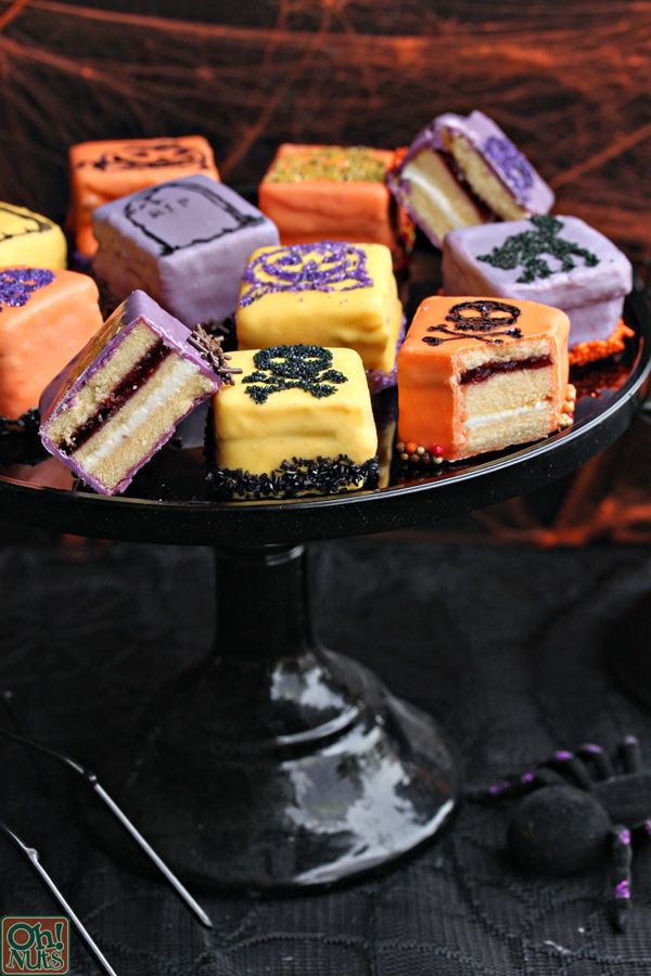 there are many different types of cakes on the cake platter with purple and orange frosting