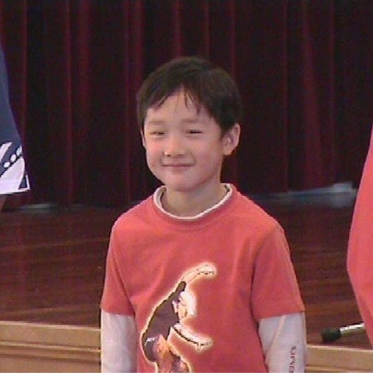 a young boy standing in front of a podium holding a nintendo wii game remote controller