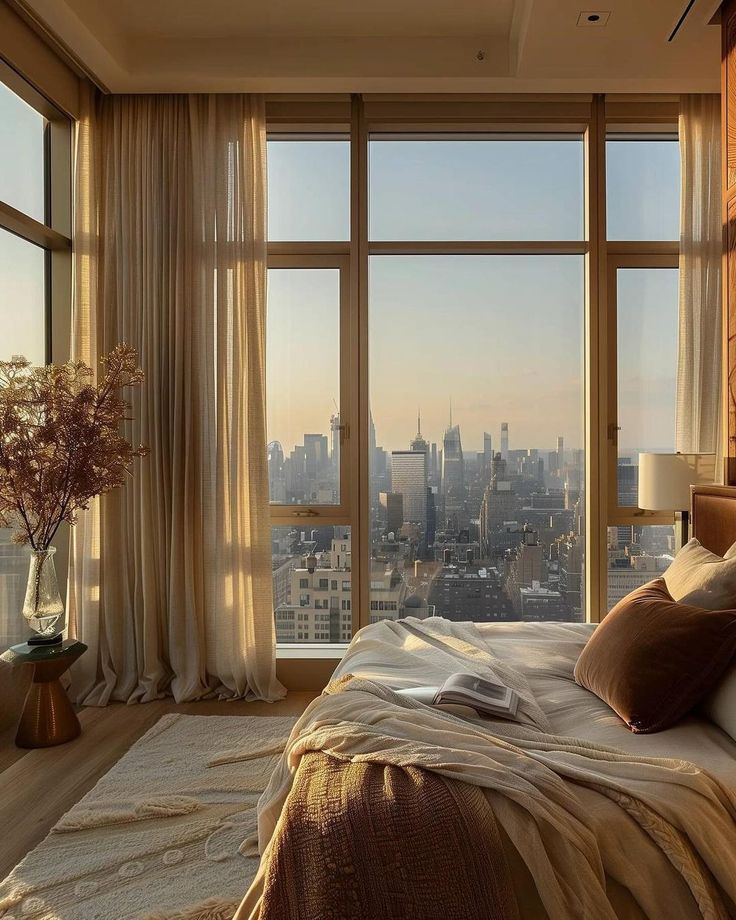 a bedroom with large windows and a view of the city from it's bed