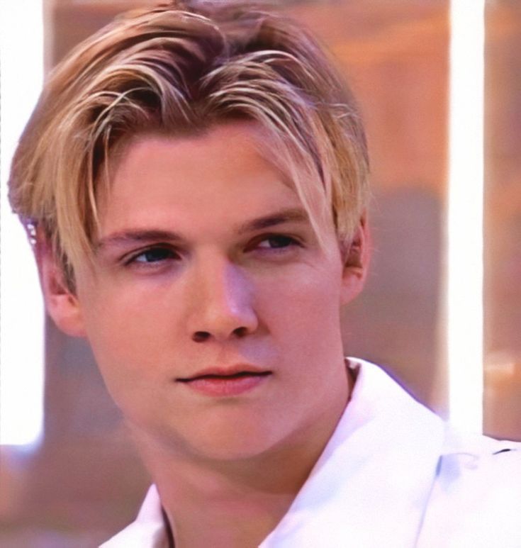 a close up of a person wearing a white shirt and looking at the camera with a serious look on his face