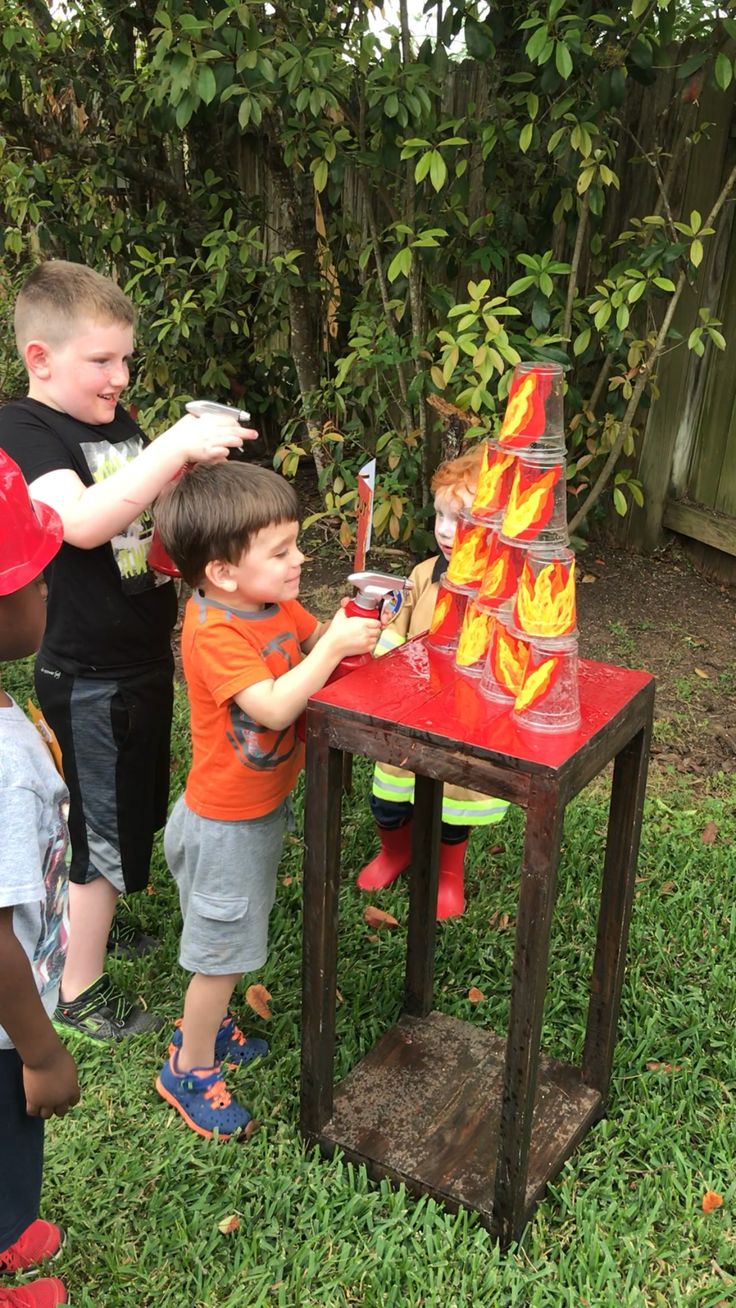 two young boys are playing with toys in the yard while another boy looks at them