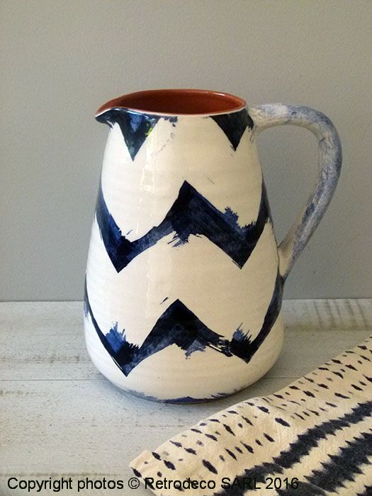 a white and blue vase sitting on top of a table next to a striped cloth