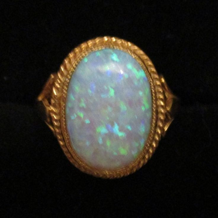 An oval-created opal Ring set in an 18ct Gold and Silver rope edge setting and Shank. Beautifully hand-made by a British professional Jewellery craftsman to the highest standard. Classic Oval Opal Ring Collectible, Heirloom Oval Cabochon Opal Ring, Antique Oval Opal Gemstone Ring, Heirloom Oval Opal Ring Hallmarked, Heirloom Oval Opal Ring Collectible, Antique Oval Opal Ring, Hallmarked Oval Opal Ring, Classic Oval Hallmarked Opal Ring, Handmade Oval Opal Ring In Yellow Gold