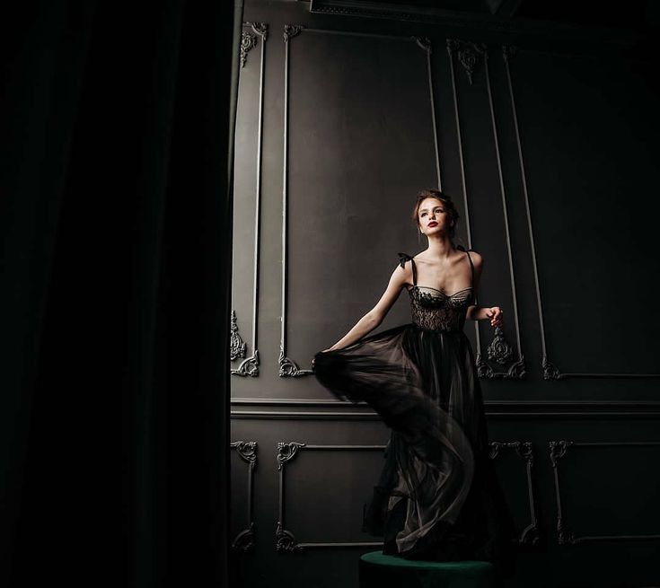 a woman in a black dress standing on a stool