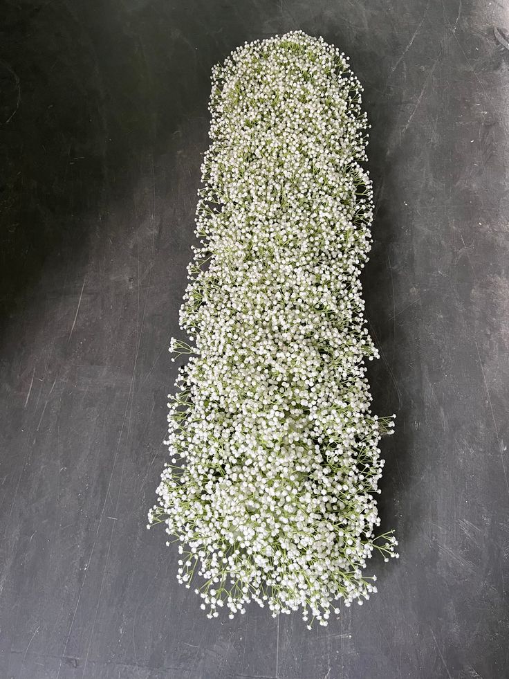 a bunch of white flowers sitting on top of a black floor next to a wall