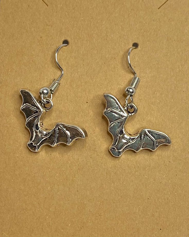 Cute little bats fluttering around at the end of a surgical stainless steel ear wire. For the dark side in all of us, what better way to say "Batty", than this.Any metals used in jewelry are all nickel free, tarnish resistant (except for copper, which will change color(patina) over time). Metals are either bare copper, silvertone, or goldtone, unless otherwise stated. Nickel-free Themed Stainless Steel Jewelry, Themed Nickel-free Stainless Steel Jewelry, Hypoallergenic Drop Earrings For Halloween, Halloween Hypoallergenic Metal Jewelry, Gothic Hypoallergenic Metal Jewelry, Novelty Metal Earrings With Ear Wire, Gothic Silver Surgical Steel Earrings, Hypoallergenic Surgical Steel Earrings, Themed Silver Earrings For Halloween