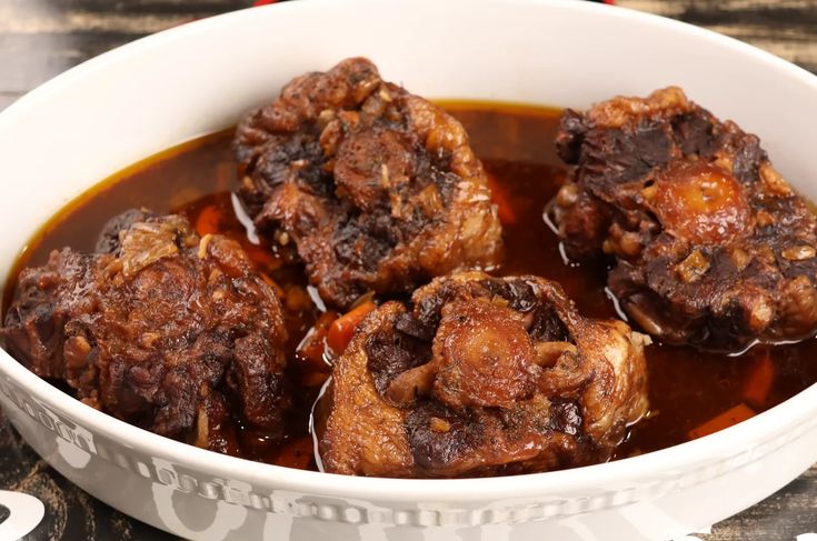 a white bowl filled with meat covered in sauce