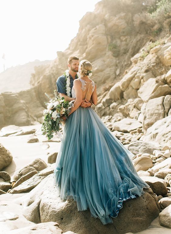 a man and woman standing next to each other on rocks