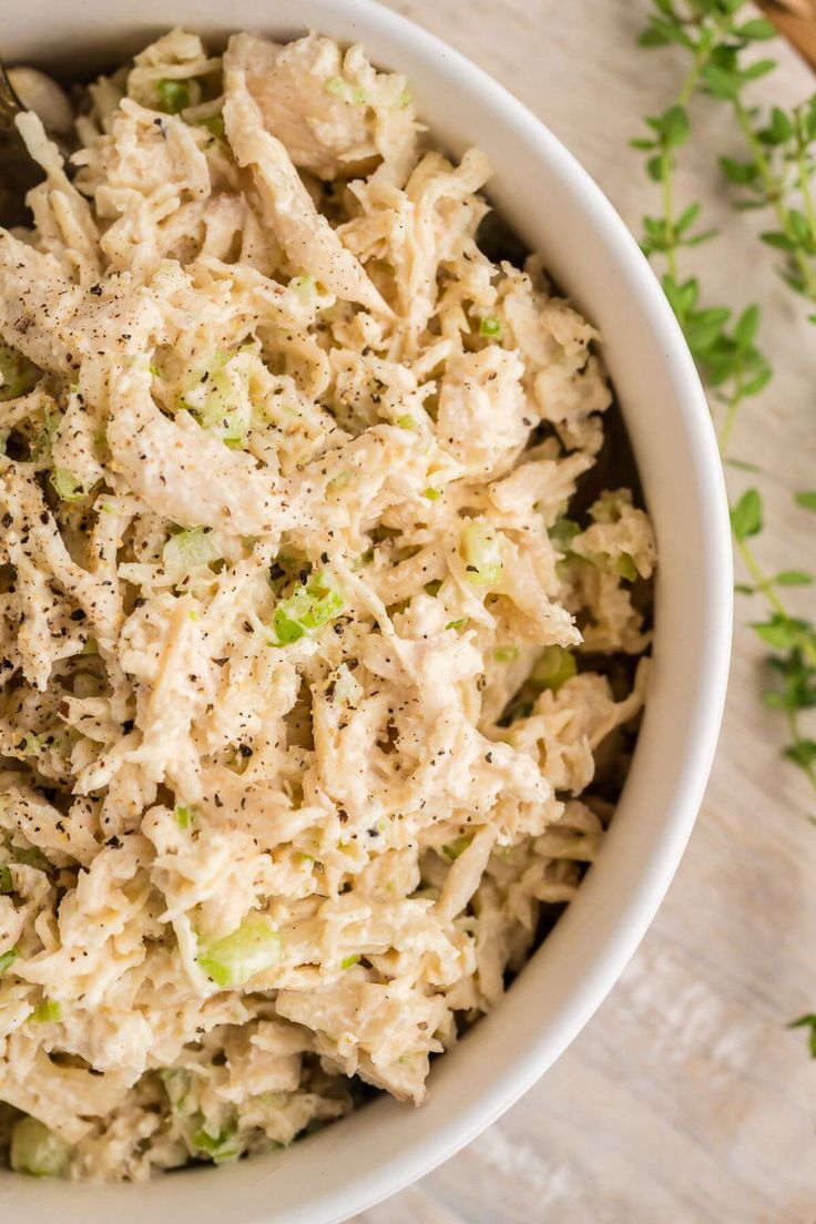 a white bowl filled with chicken salad on top of a table