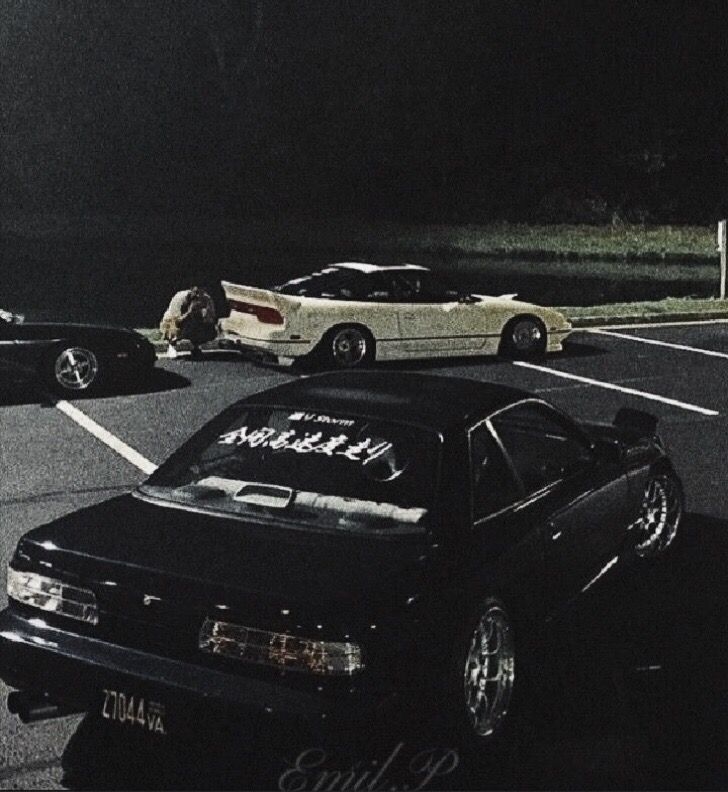 two cars parked in a parking lot at night