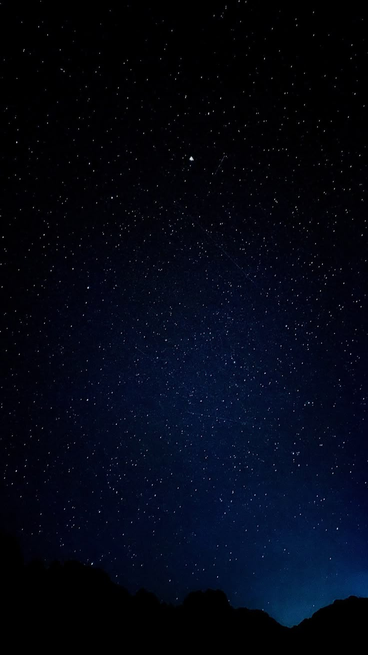 the night sky is full of stars and there are mountains in the foreground below