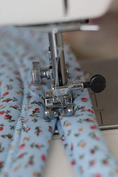 the sewing machine is working on the blue flowered fabric that has been sewn