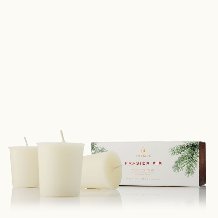 three white candles sitting next to a box