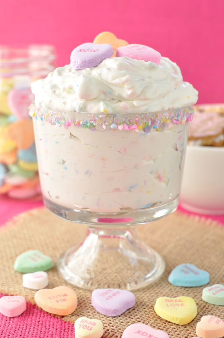 a cupcake with white frosting and candy hearts