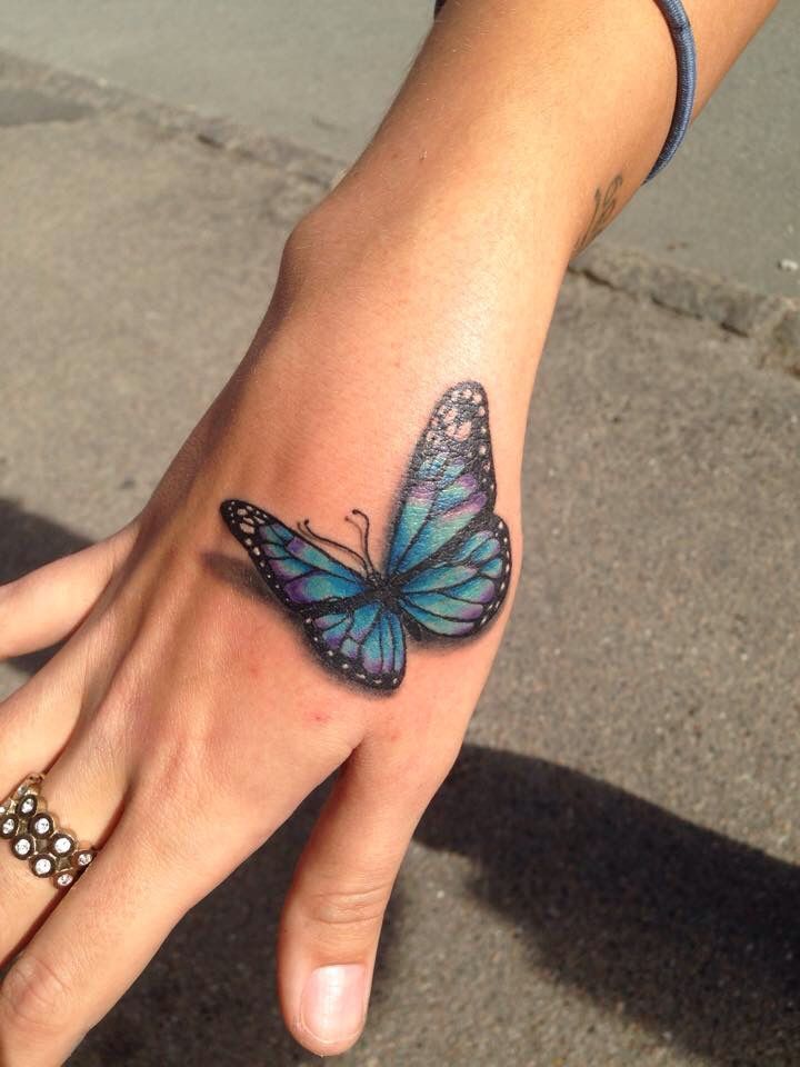 a woman's hand with a blue butterfly tattoo on the left wrist and right hand