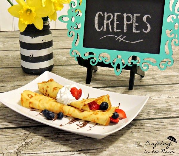 crepes with berries and whipped cream on a plate in front of a chalkboard sign