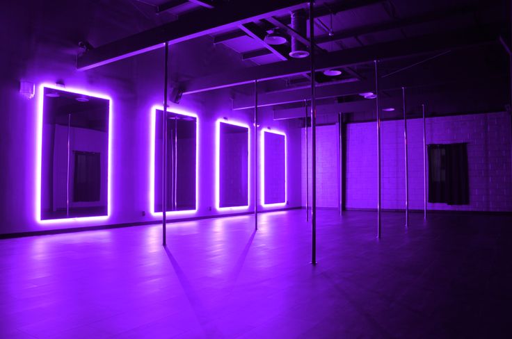 an empty room with purple lighting and mirrors