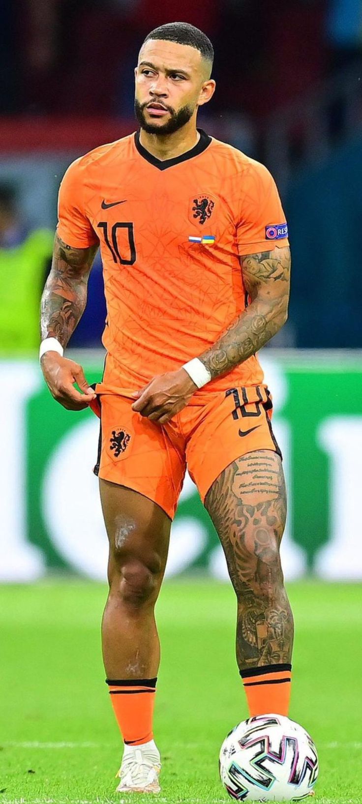 a man with tattoos standing next to a soccer ball