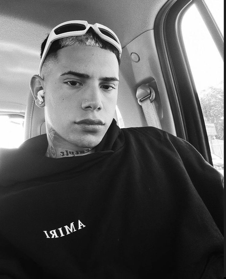 a young man sitting in the back seat of a car with sunglasses on his head